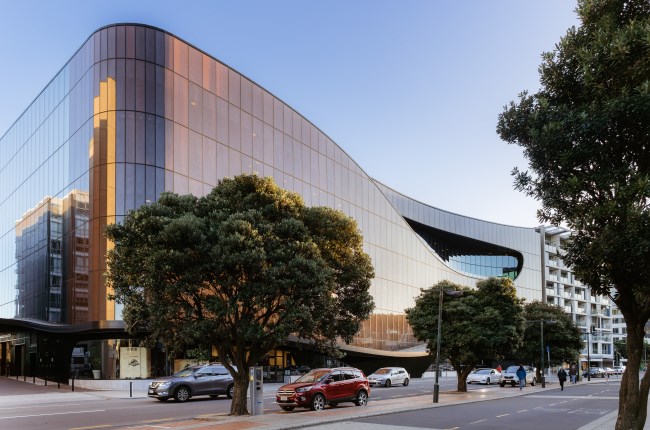 Large glass building with trees reflected in the windows. 