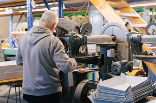 A person working an industrial sized staple machine.