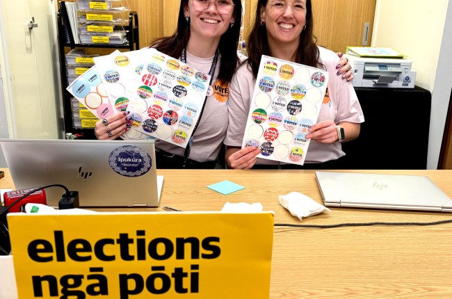 Council kaimahi at election hub at Te Awe library with stickers for voters.