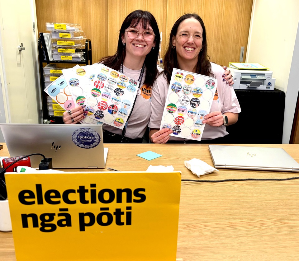 Council kaimahi at election hub at Te Awe library with stickers for voters.