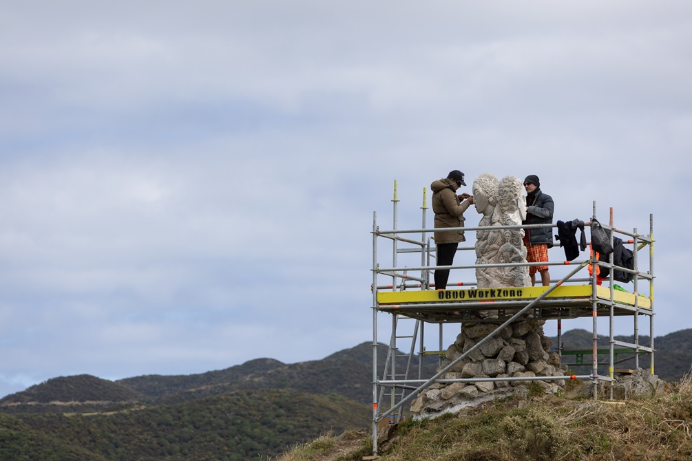 Photo of Ariki and Matahi working on the pou while standing on scaffolding in the wind