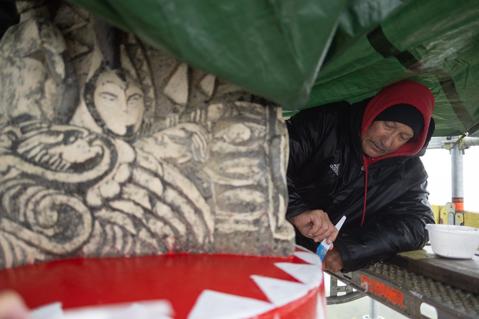 Close-up of Matahi adding the new red and white patterns at the bottom of the pou to symbolise the connection betwen Aotearoa and the rest of the Pacific