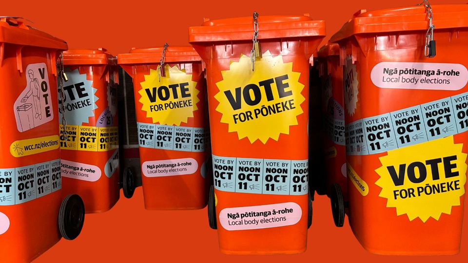 Orange voting bins with stickers plastered all over with details about voting