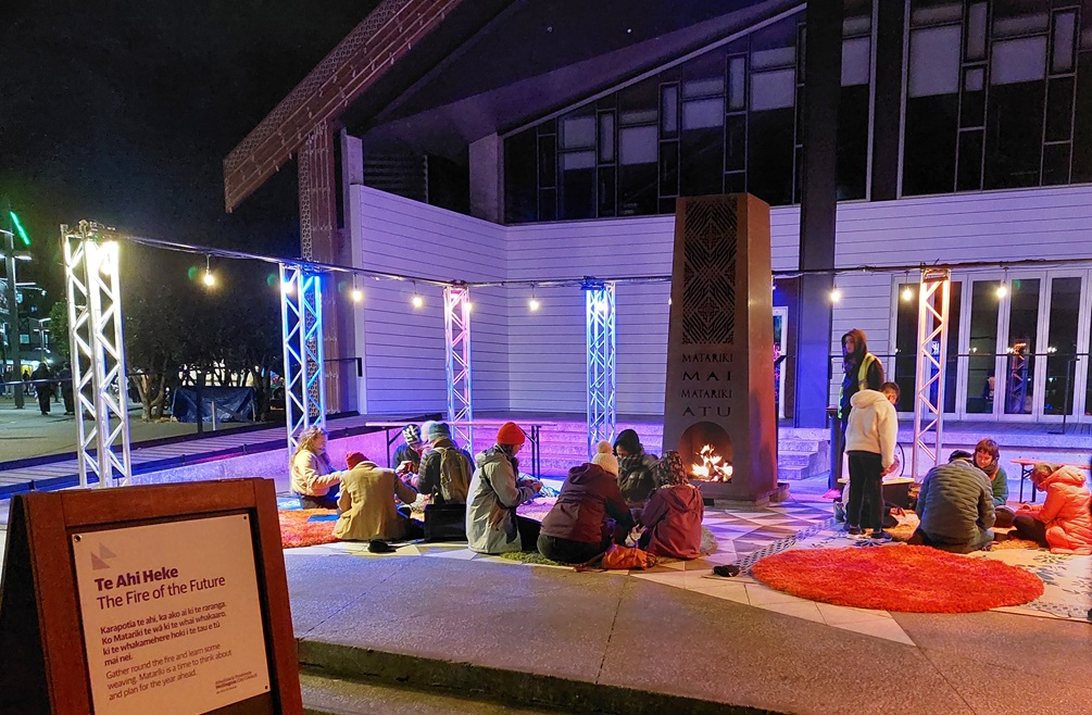 Families sitting together in front of a large metal brazier.