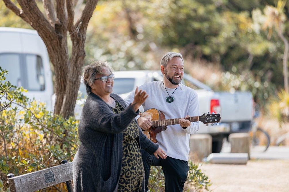 Two people singing, one playing the guitar.