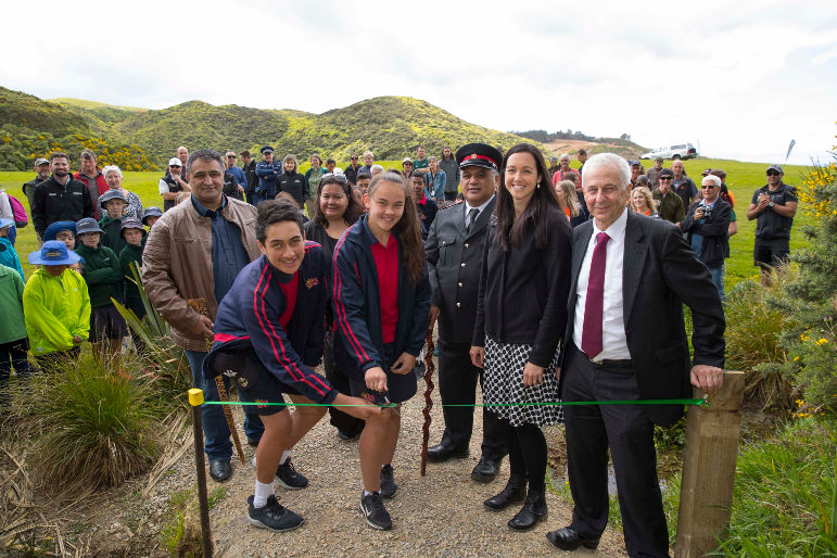 A group of people in front of a green ribbon.