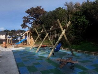 Burbank Crescent play area with a series of swings and a blue slide featured in the distance.