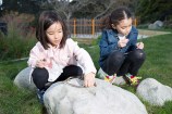 Two young girls arranging sticks on top a stone.