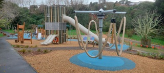 A newly constructed playground with rope swings, a tower and slide visible.