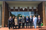 Japanese delegation and members of Te Runanganui standing in front of a building with maori carvings.
