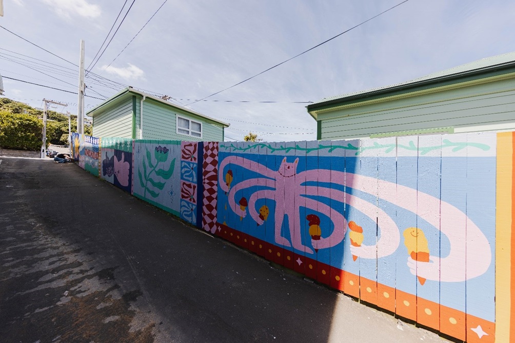 Island Bay shopping centre pedestrian accessway through to Clyde Street showing the colourful mural painted on the fence.