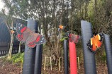 Wooden posts painted black and red, with brightly coloured wooden butterflies attached as if they were perching on branches.
