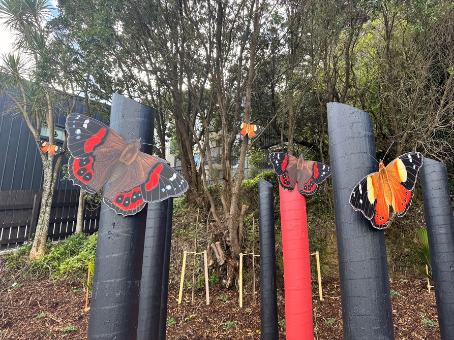 Wooden posts painted black and red, with brightly coloured wooden butterflies attached as if they were perching on branches.