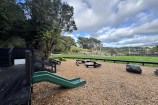 View of the park looking towards the zoo, showing a low slide and nature play area.