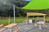 The seating area of the park, with picnic tables and barbeque stations under a decorative wooden shelter.