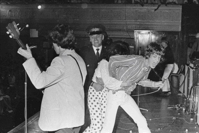 Police restraining a fan who has seized Mick Jagger during a Rolling Stones concert at the Town Hall in 1966.