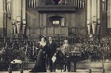 Performers on the stage in Wellington Town Hall, with the organ behind them.